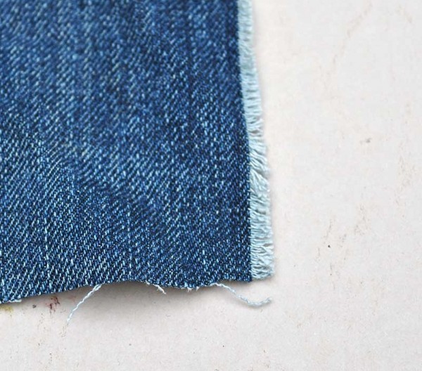 Bước 3.  Bạn dùng tay kéo léo kéo một số sợi màu xanh da trời lỏng lẻo để lộ sợi trắng xuống một bên của mảnh vải.