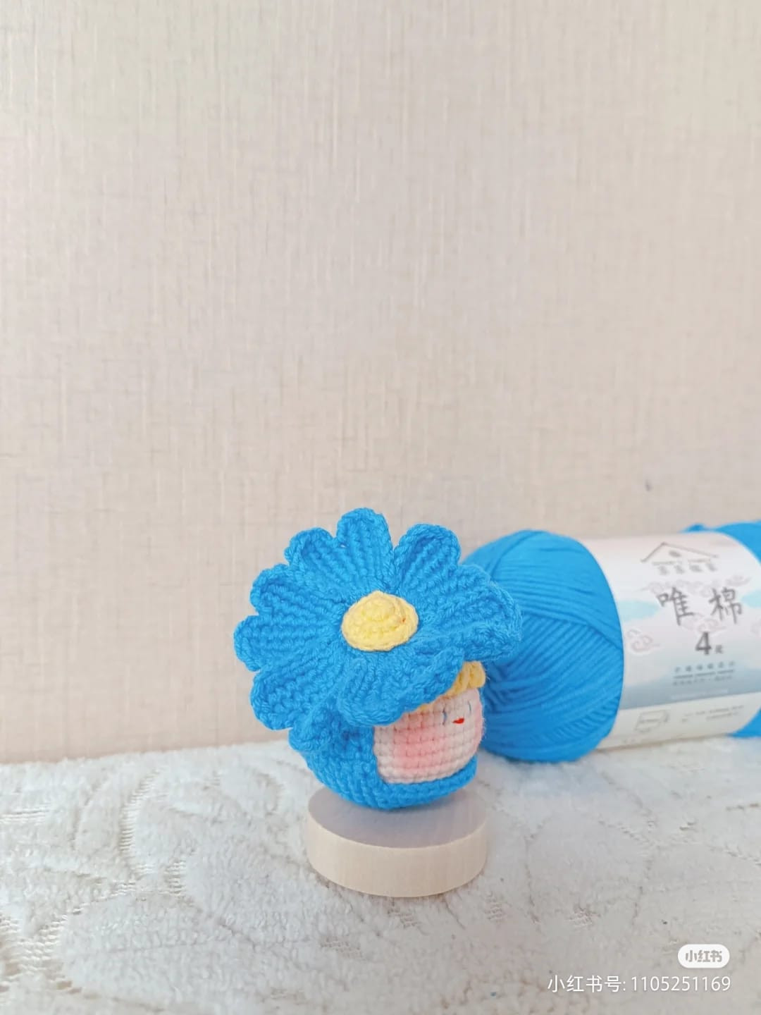 Crochet pattern for a doll's head wearing a blue flower hat