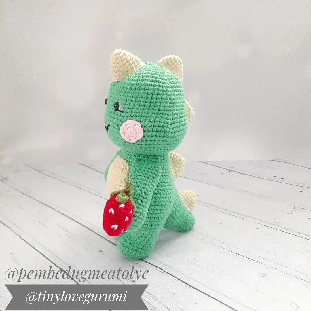 blue dinosaur, white belly, pink cheeks, red strawberry in hand, blue stem dino afacan free crochet pattern