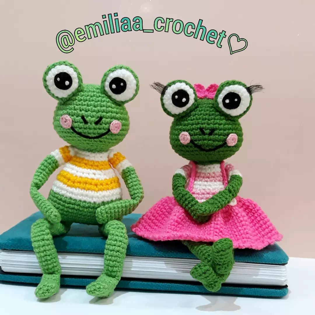 free crochet pattern green frog couple with bulging eyes, wearing pink skirt, wearing overalls.
