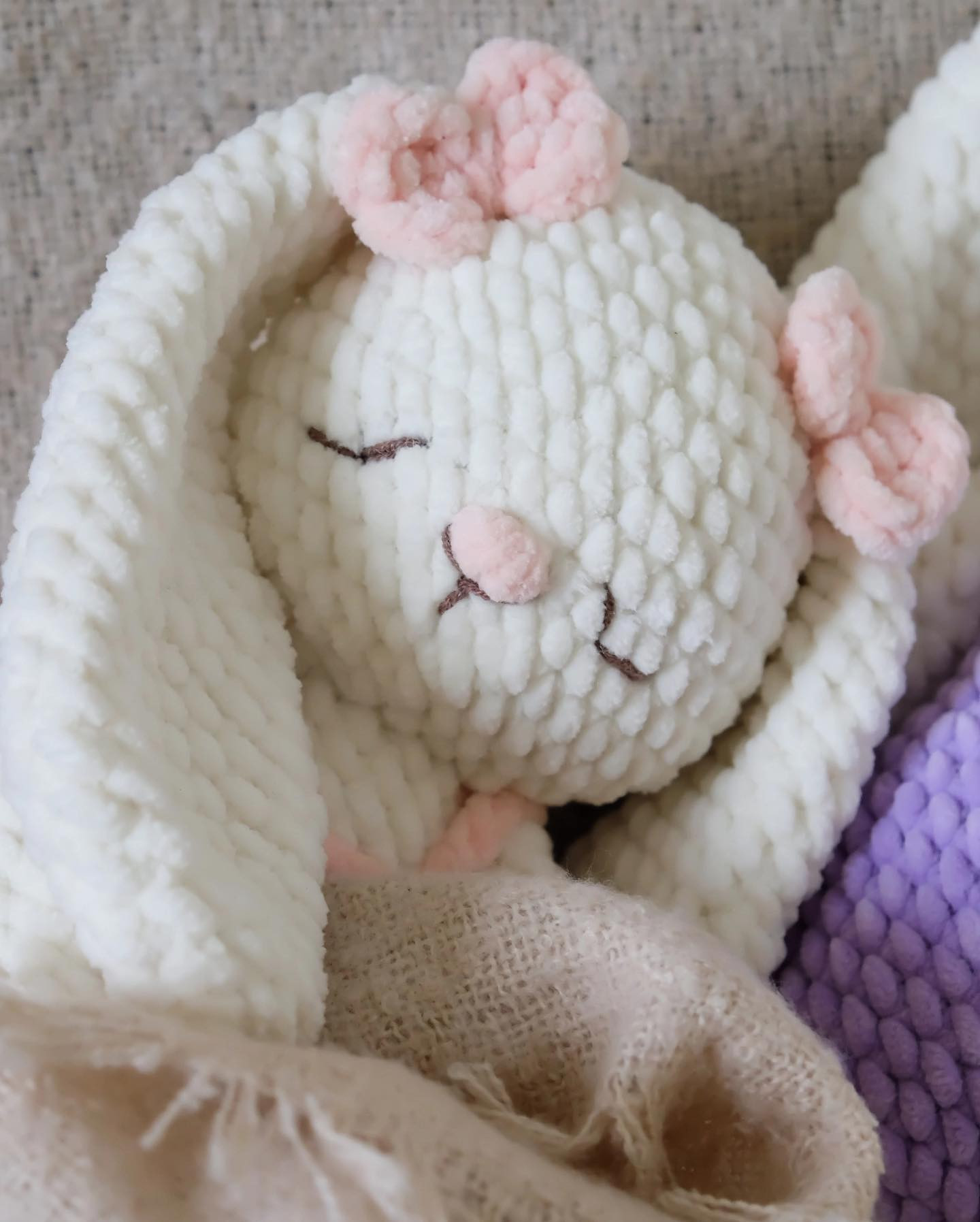 white rabbit, long ears wearing pink overalls, purple crochet pattern overalls
