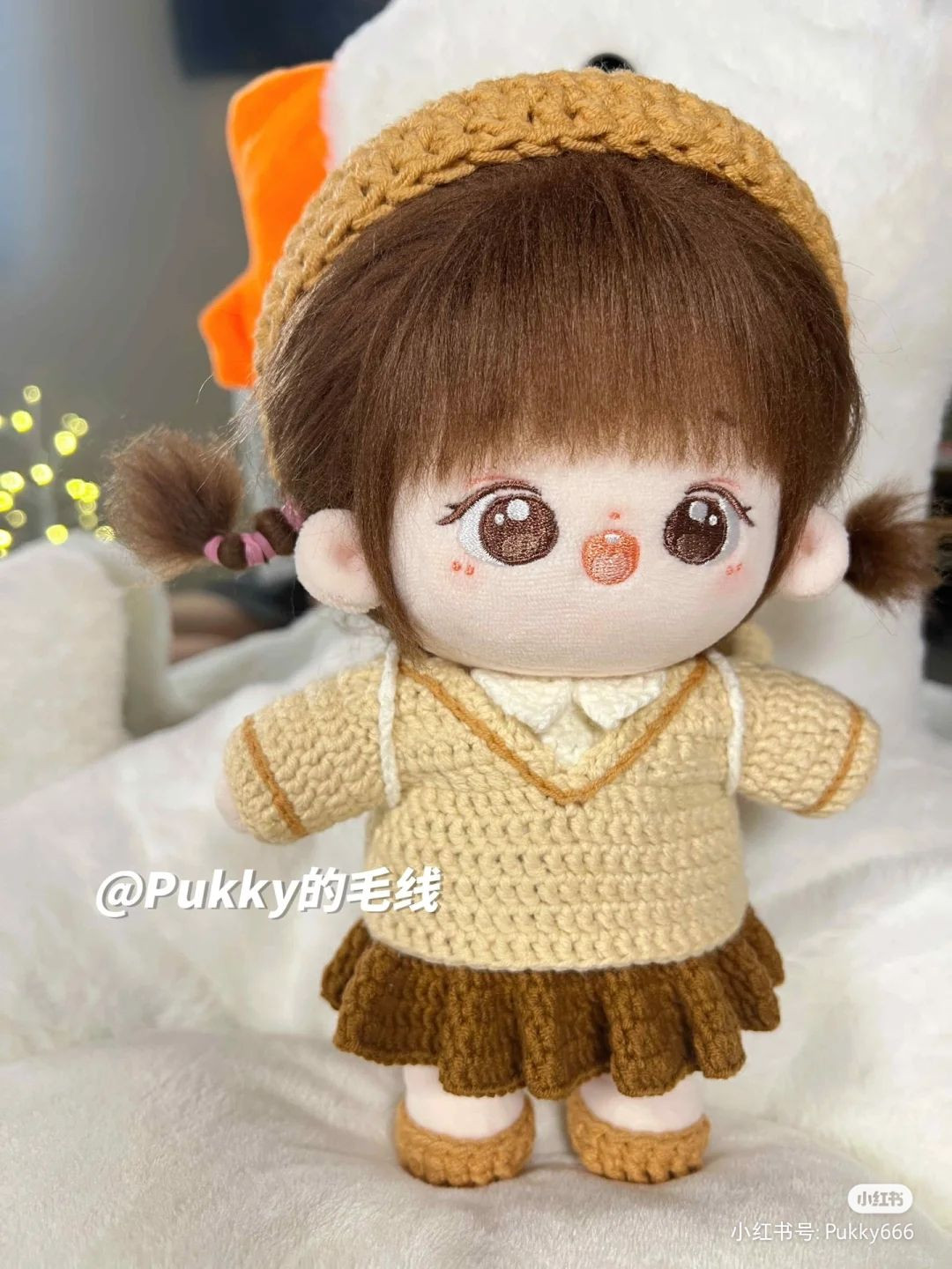 Brown-haired girl doll wearing a brown beanie and a brown dress.