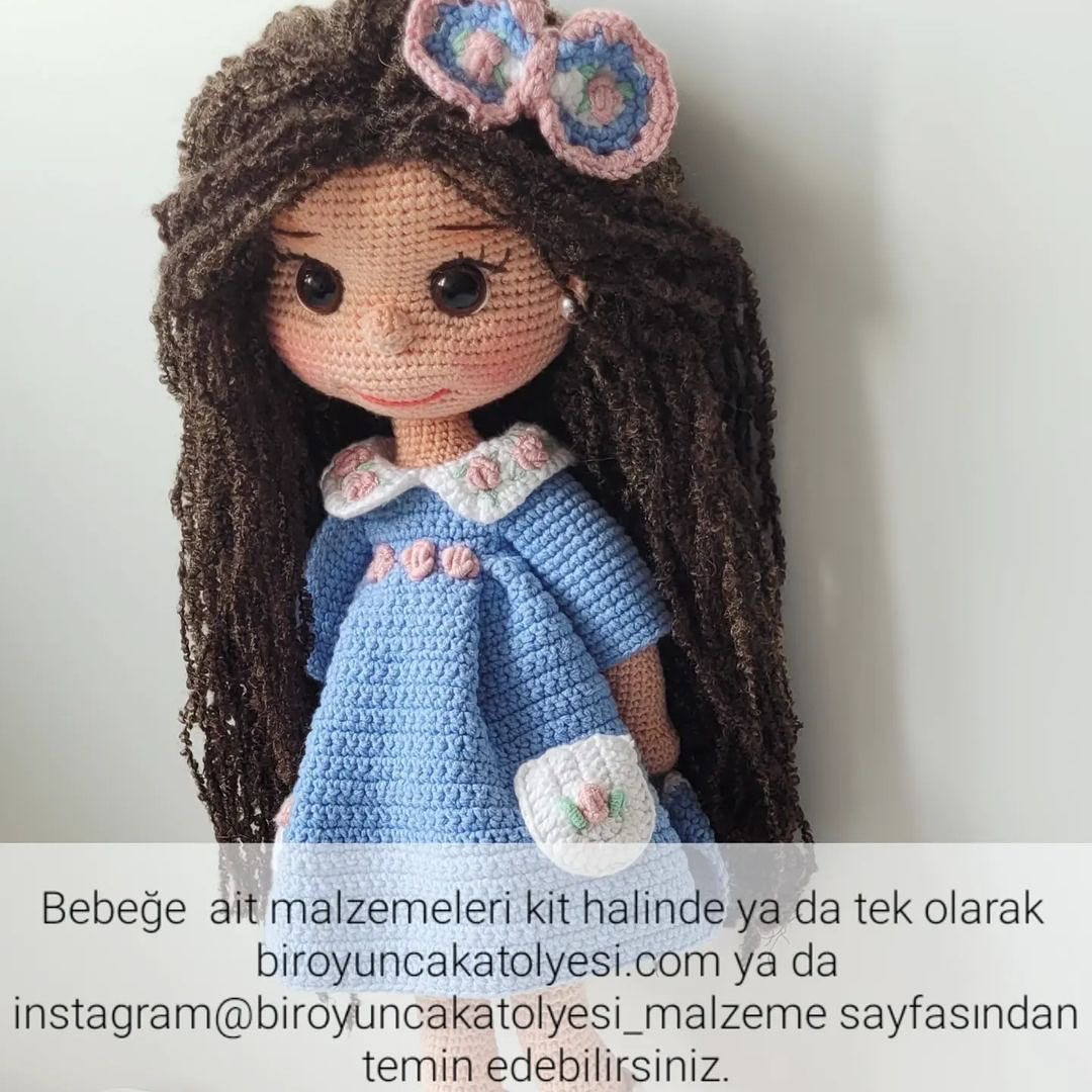 Kahverengi saçlı ve mavi elbiseli bir bebek için tığ işi modeli.