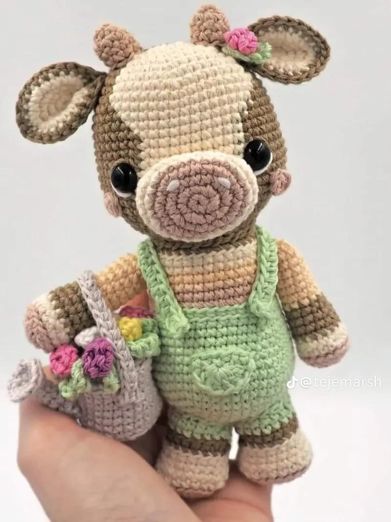 Muñeca de vaca amigurumi con vestido verde y regadera de flores