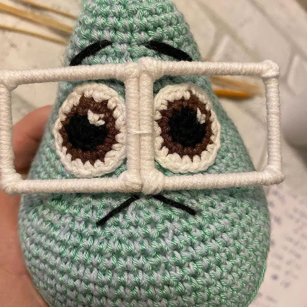 Вязаная игрушка с очками на фоне зимнего пейзажа
