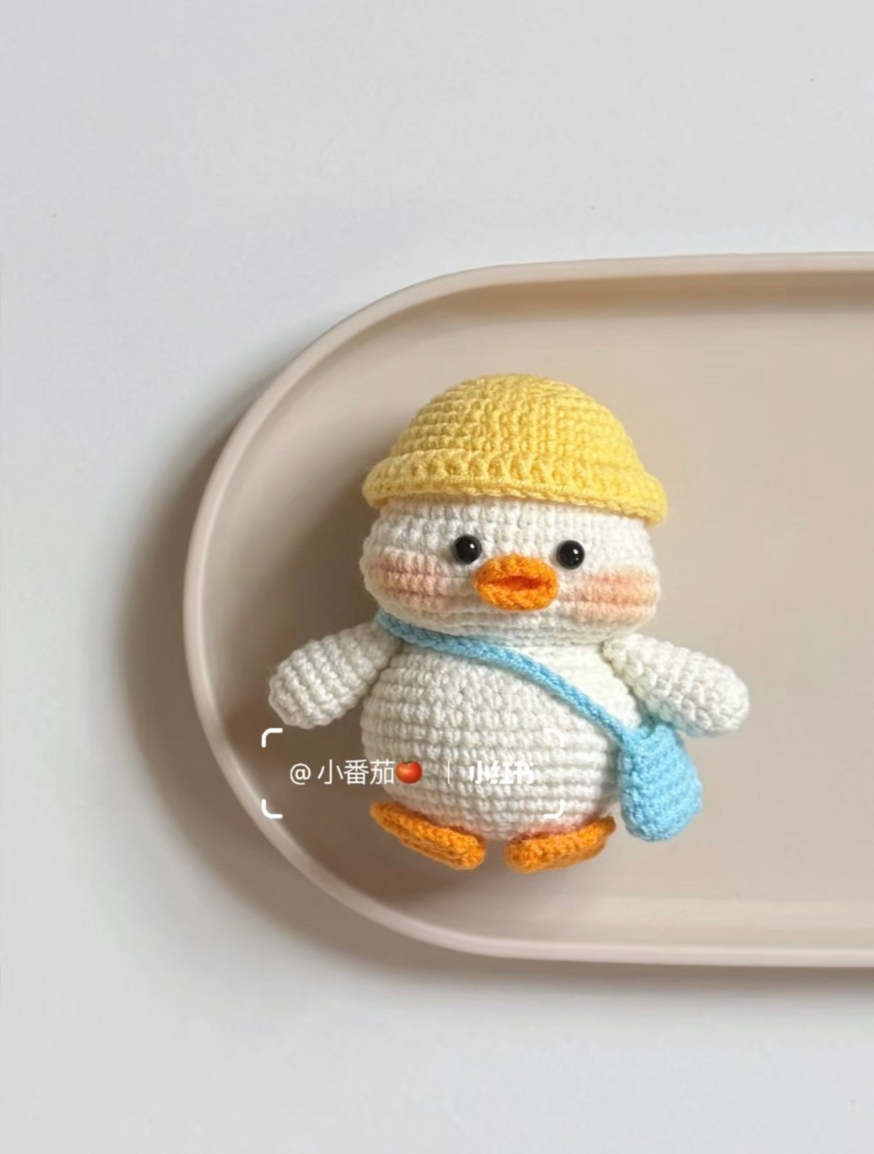 Chú vịt len nhỏ xinh đội mũ vàng cầm túi xanh