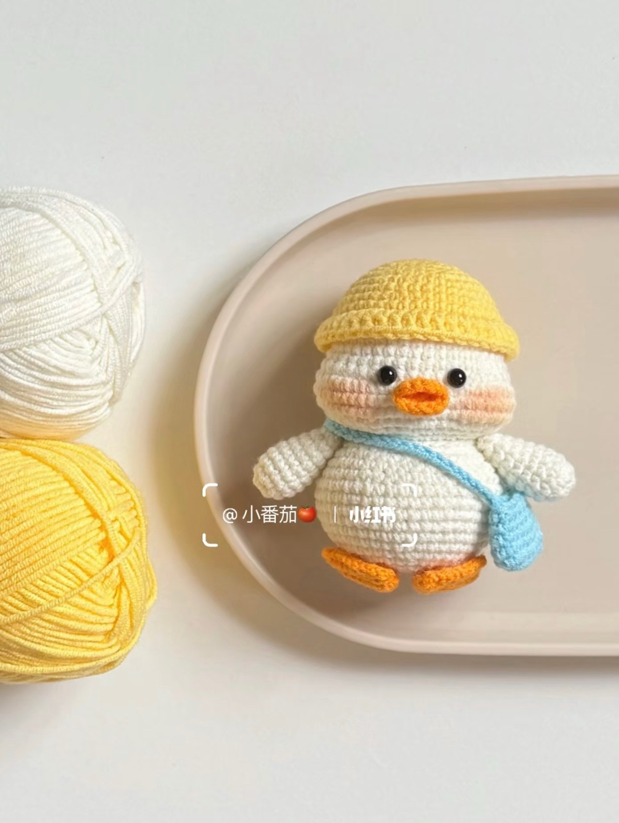 Chú vịt len nhỏ xinh đội mũ vàng cầm túi xanh