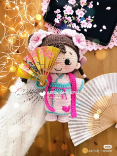 Black hair doll crochet pattern, wearing a skirt, holding a fan.