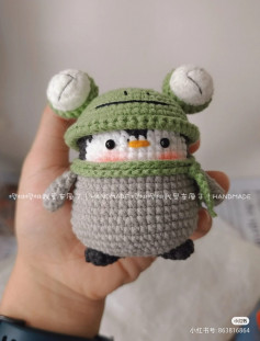 Penguin crochet pattern wearing green frog hat.