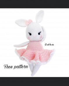 White rabbit crochet pattern wearing a pink skirt with ears and bows.