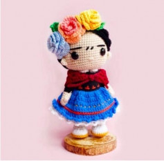 Boy doll with flowers on his head, wearing a blue crochet pattern shirt and skirt