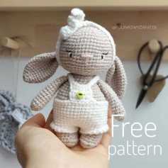Crochet pattern of crocheted rabbit doll wearing white overalls and a scarf.