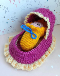 baby sleeping in purple crib, wrapped in yellow crochet pattern