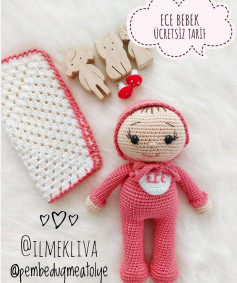 free crochet pattern doll wearing pink hat, pink clothes, white chest with bib.