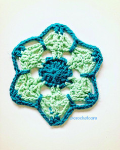 free crochet pattern in the shape of a six-petaled flower with a circle in the center.