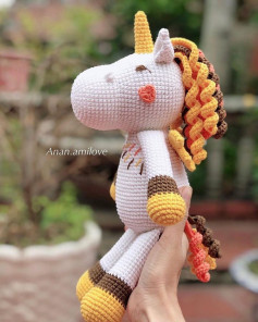 The unicorn horse is white, has yellow horns, yellow legs and arms, yellow, brown, and pink mane.