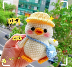 White duck wearing a yellow hat, blue crochet pattern crossbody bag