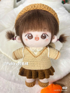 Brown-haired girl doll wearing a brown beanie and a brown dress.
