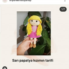 Sarı saçlı ve pembe elbiseli bir bebek için tığ işi modeli.