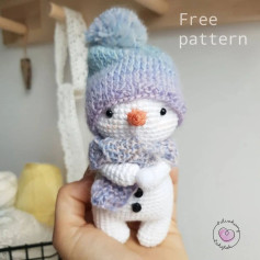 Crochet pattern for a snowman wearing an orange hat and scarf