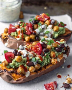 Simple, delicious, Baked Sweeties with black beans, chickpeas, tomatoes, guacamole, and drizzles of dilly hummus and sriracha 🥔🥬⠀⠀⠀