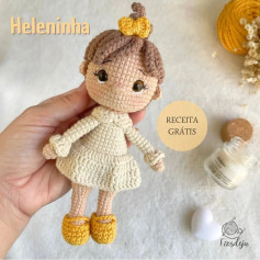 Modelo de boneca em crochet com vestido branco e laço amarelo.