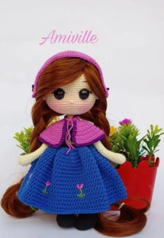 Muñeca amigurumi vestida de azul y rosa con flores.