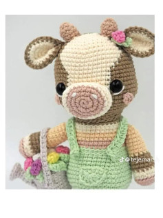 Muñeca de vaca amigurumi con vestido verde y regadera de flores