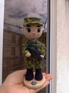 Muñeco amigurumi de soldado con uniforme camuflado y rifle a escala