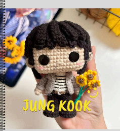 Pequeño muñeco amigurumi con flores amarillas, perfecto para regalar.