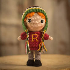 Brinquedo de crochê com chapéu colorido e letra R no vestido