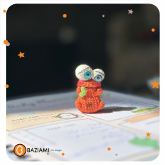 متن بافتنی عروسک کوچک با چشمان بزرگ و لباس نارنجی