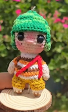 Muñeco amigurumi con sombrero verde y ropa a rayas