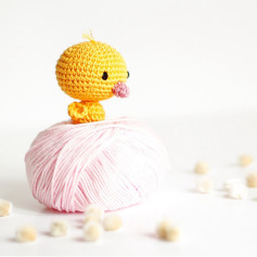Petit canard en crochet sur une pelote de laine rose