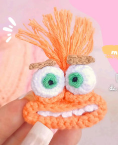 Divertido monstruo de ganchillo con ojos grandes y cabello naranja