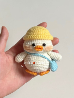 Chú vịt len nhỏ xinh đội mũ vàng cầm túi xanh