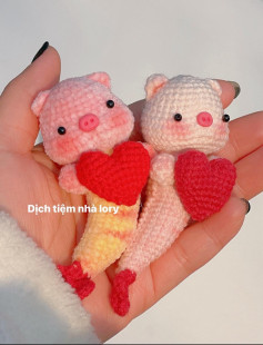 Hai chú heo móc len cầm trái tim trong tay