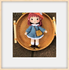 Muñeca de crochet con vestido azul y bolso marrón