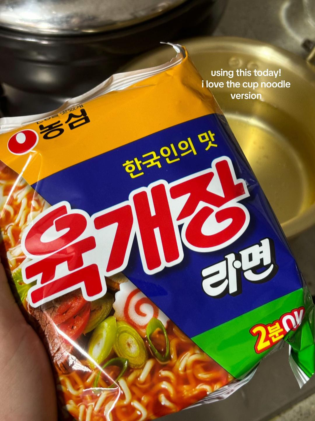 Cooking Nongshim Yukgaejang Ramyeon with kimchi and vegetables in a brass pot