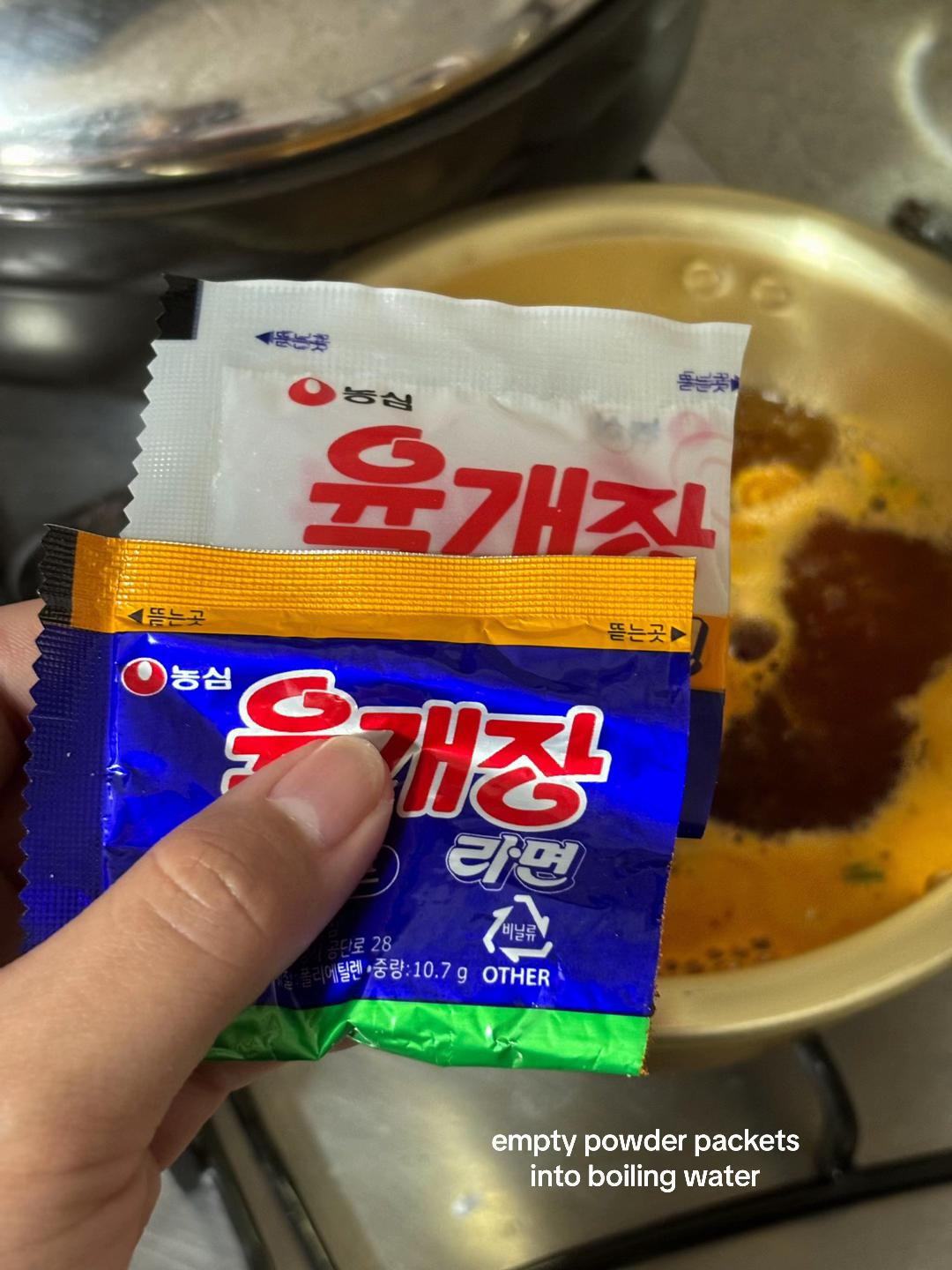 Cooking Nongshim Yukgaejang Ramyeon with kimchi and vegetables in a brass pot