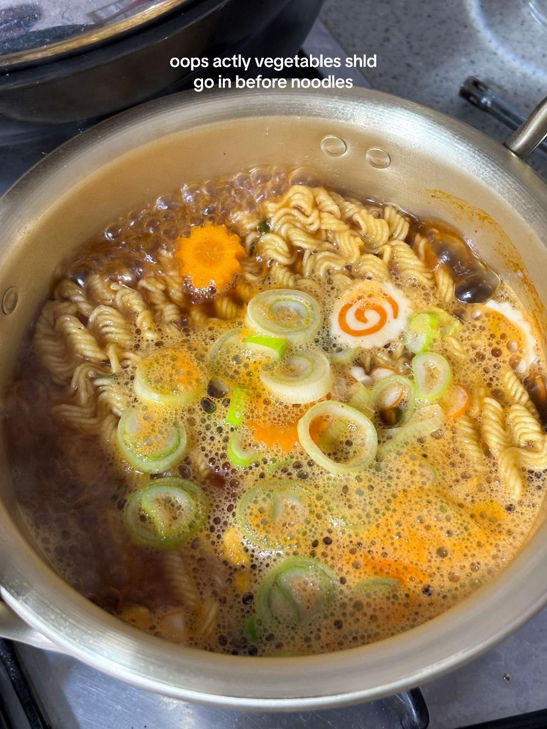 Cooking Nongshim Yukgaejang Ramyeon with kimchi and vegetables in a brass pot