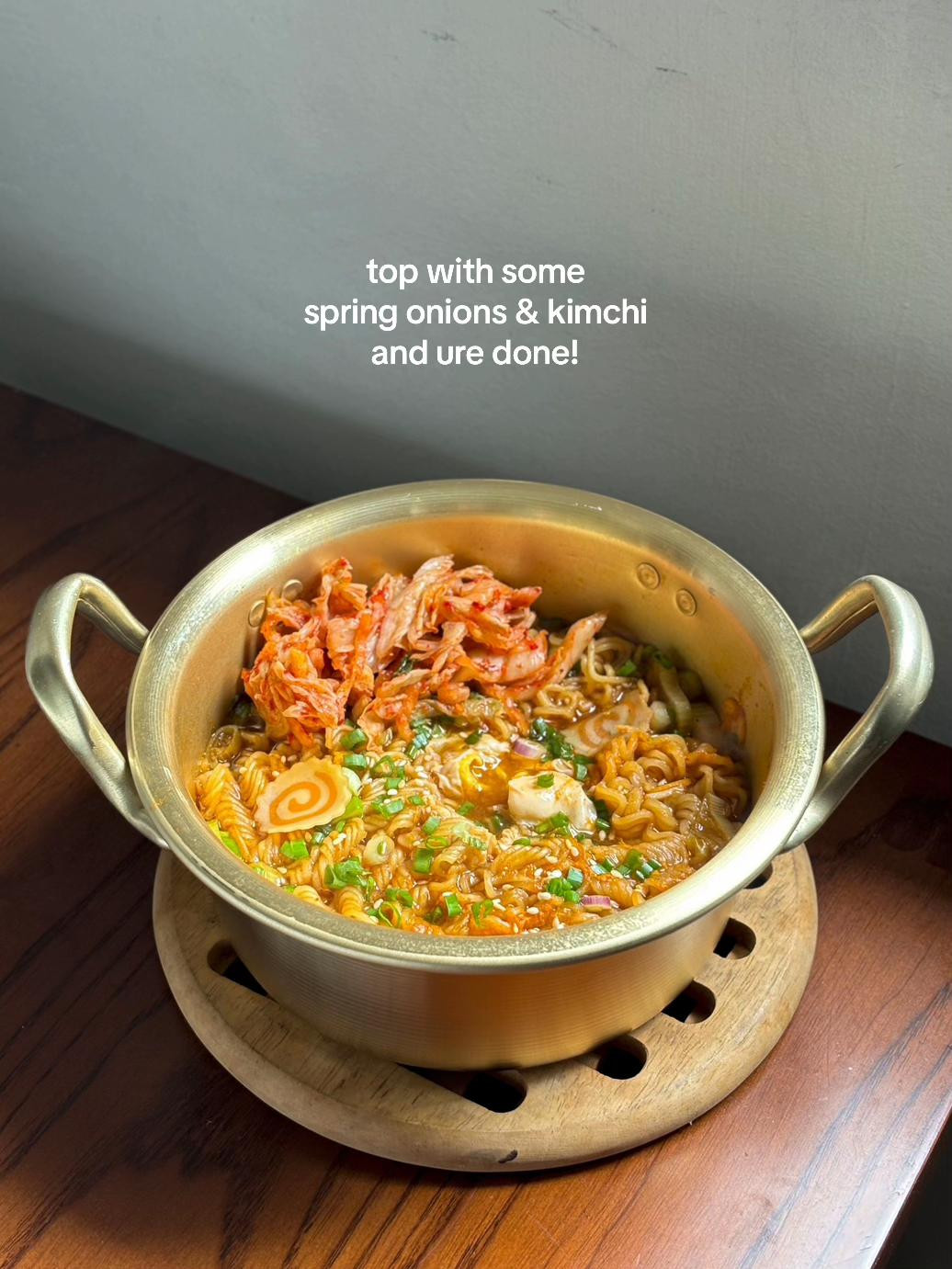 Cooking Nongshim Yukgaejang Ramyeon with kimchi and vegetables in a brass pot