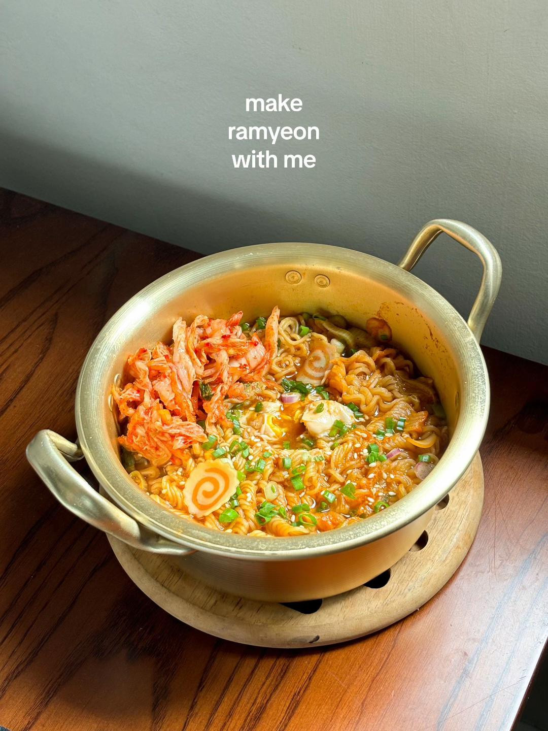 Cooking Nongshim Yukgaejang Ramyeon with kimchi and vegetables in a brass pot