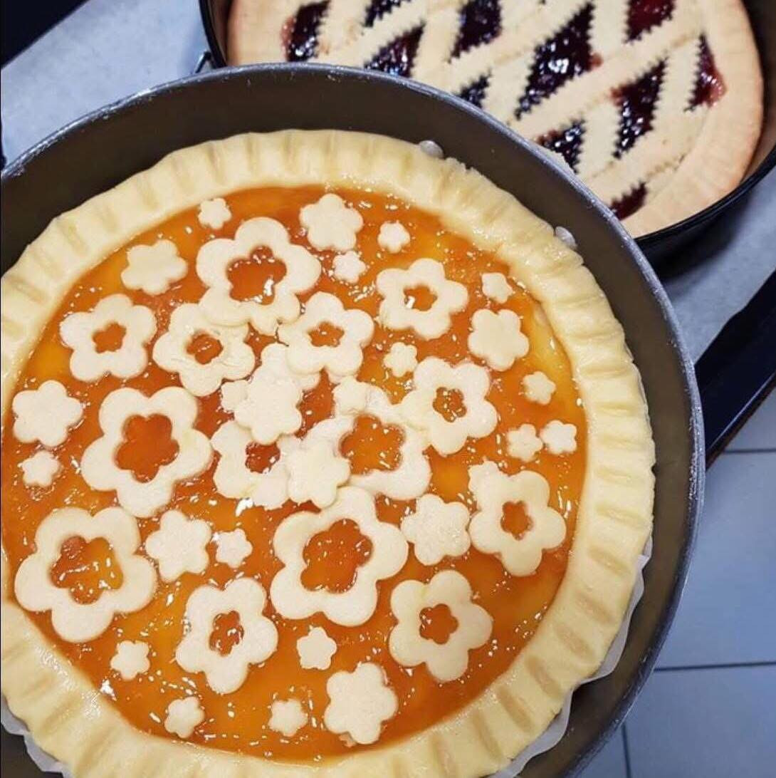 Crostata di pasta frolla con marmellata di albicocche e ciliegie decorata a fiore e intreccio