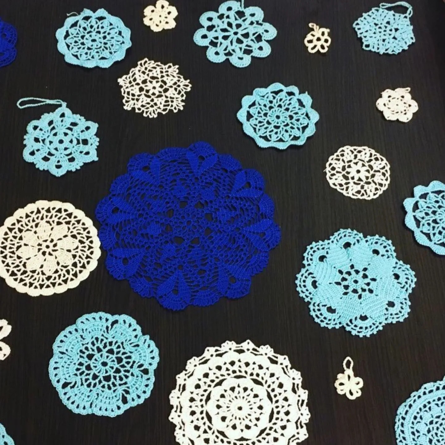 Gợi ý đồ trang trí handmade: Bộ mẫu móc len (crochet chart) khăn trải bàn hình tròn tinh xảo với các màu xanh dương, trắng và kem