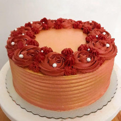 Bolo decorado com flores de chantilly vermelho e detalhes dourados