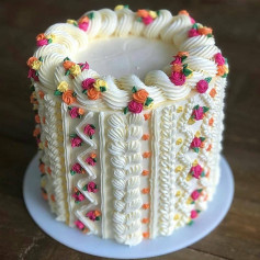 Delicious buttercream cake decorated with colorful flowers and intricate piping patterns
