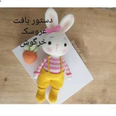 دستور بافت عروسک خرگوش سفید با لباس راه‌راه صورتی و شلوار زرد